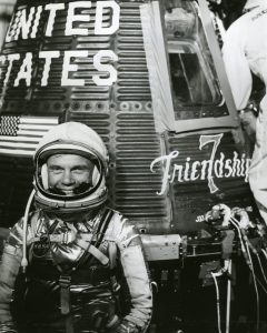 John Glenn sitting beside the Friendship 7 spacecraft, 1961