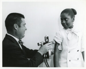 A Columbus student is shown receiving a vaccination shot for rubella using a jet injection gun in May 1970