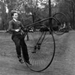 Black and white photograph of a man operating a high wheeler bicycle.