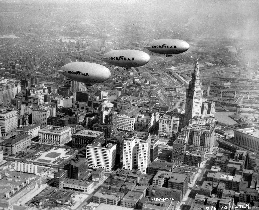 Three Goodyear Blimps flying over Cleveland, Ohio skyline. Black and white photograph.