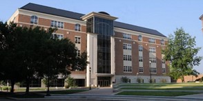 A photograph of a large brick building with large window over the entry. This is the Kettering Labs at the University of Dayton.
