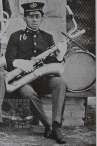 Black and white photograph of a man in a uniform holding a musical instrument.